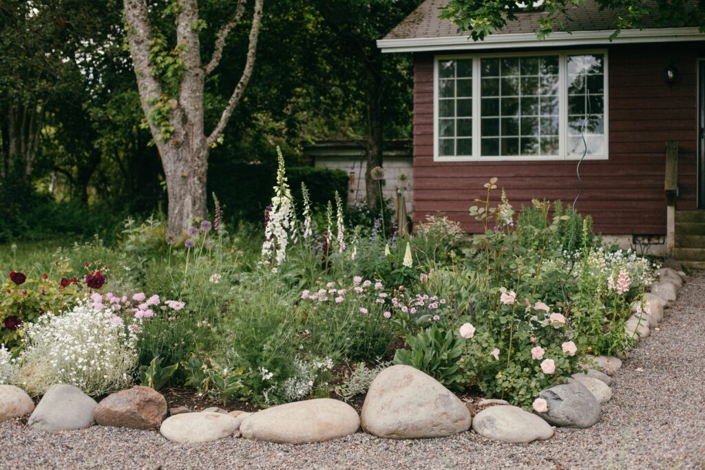 Photo of cottage style flower bed in front of a red Swedish Cottage