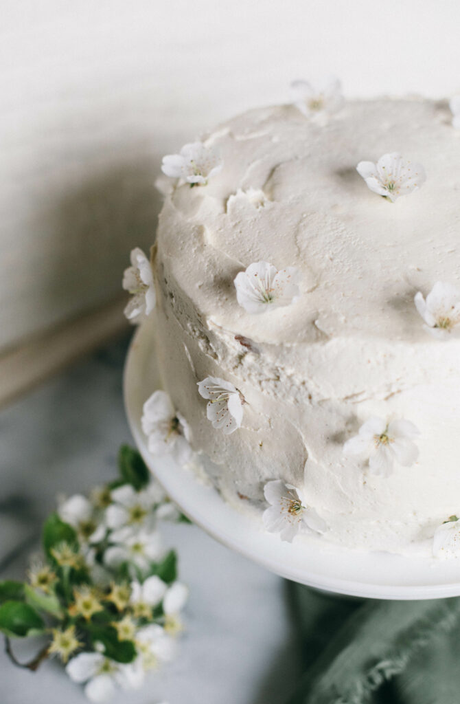 Overhead photo of a white Einkorn Sponge Cake topped with cherry blossoms