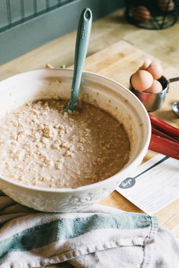 Photo of a bowl of Sourdough Rhubarb Baked Oatmeal being mixed up before being baked in a white bowl with a GIR Spatula