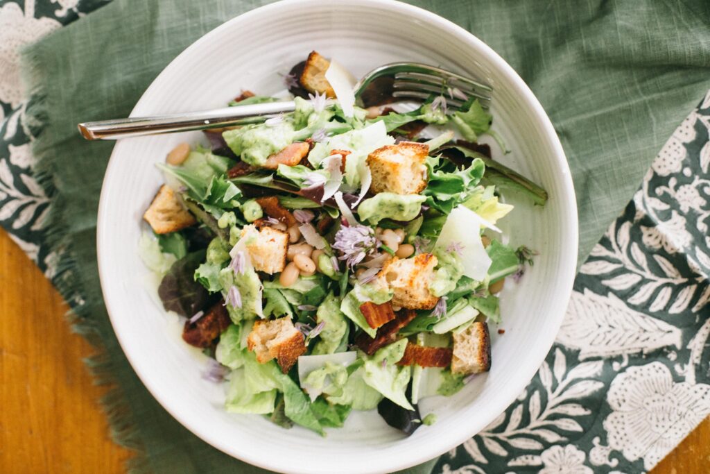 Image of a Garden Chop Salad with Green Goddess Dressing in a white salad bowl on a green floral napkin