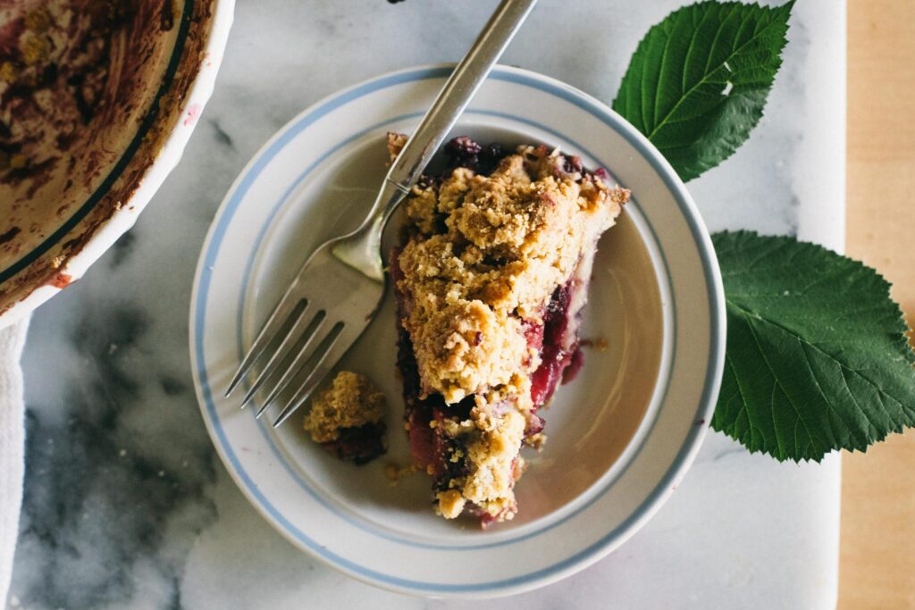 Image of a slice of Blackberry Apple Crumble Pie on a small plate with a blue rim fantastic desserts