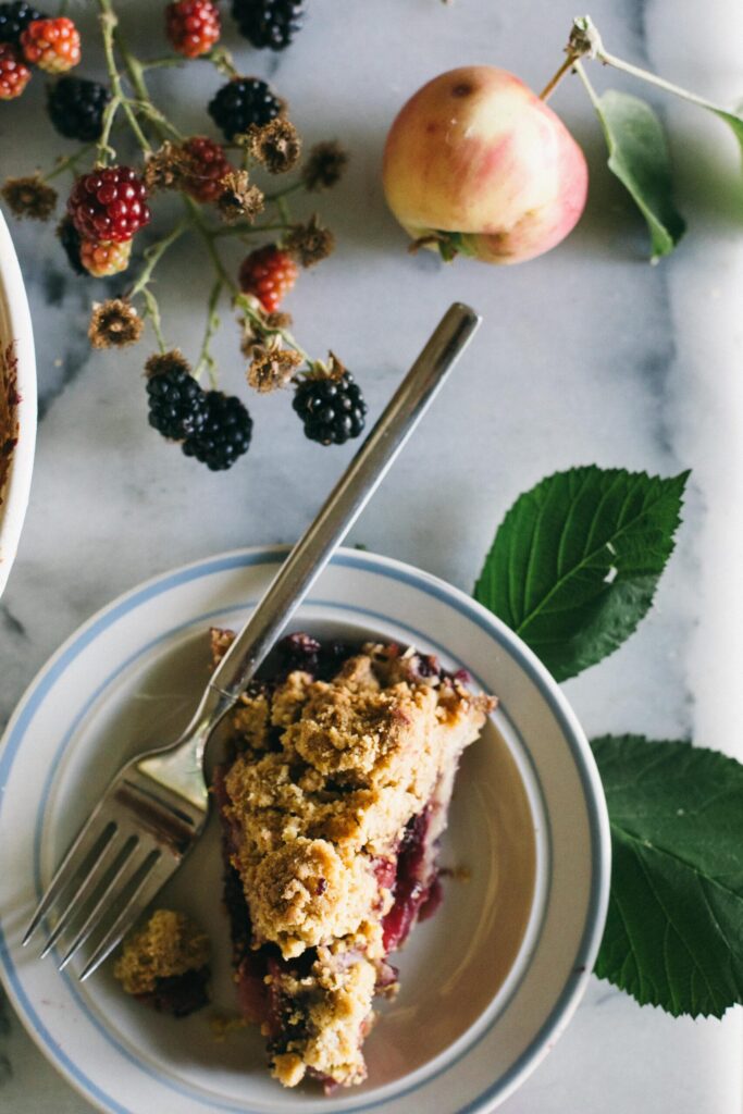 Image of a slice of Blackberry Apple Crumble Pie on a small plate with a blue rim fantastic desserts