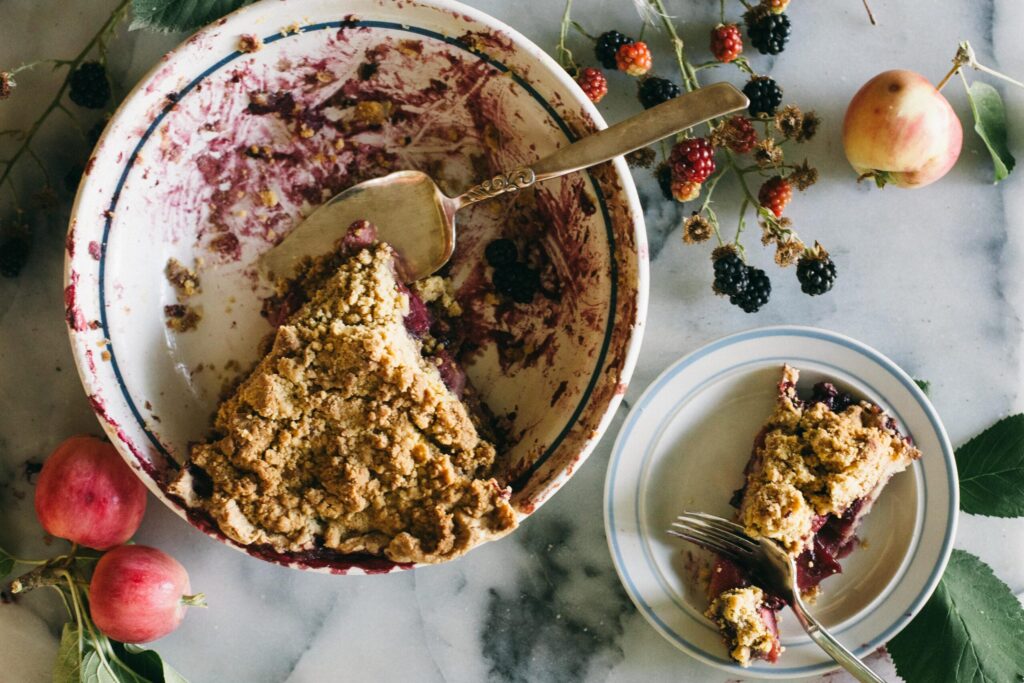 Image of a Blackberry Apple Crumble Pie on a marble board with apples and berries fantastic desserts