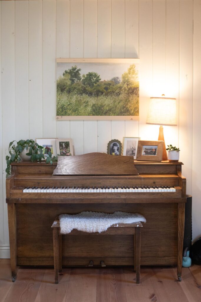 Image of a secondhand piano with picture frames and impressionist art