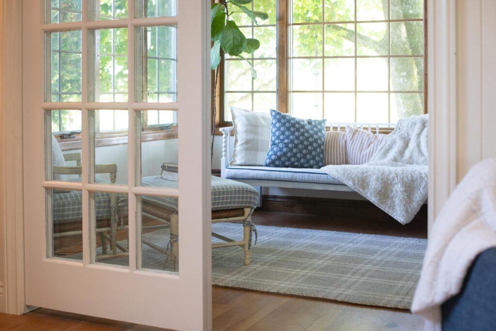 Image of a Swedish Cottage Sunroom filled with secondhand furniture, cozy pillows and blankets