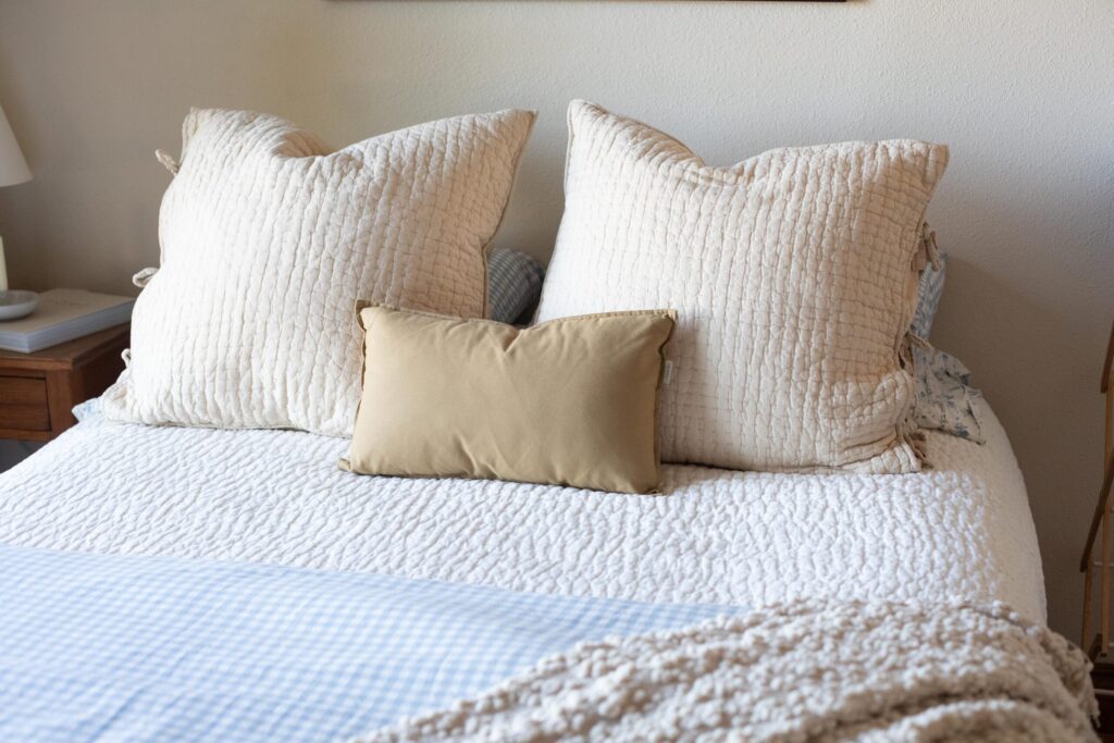 Image of a bed dressed in soft, neutral secondhand linens