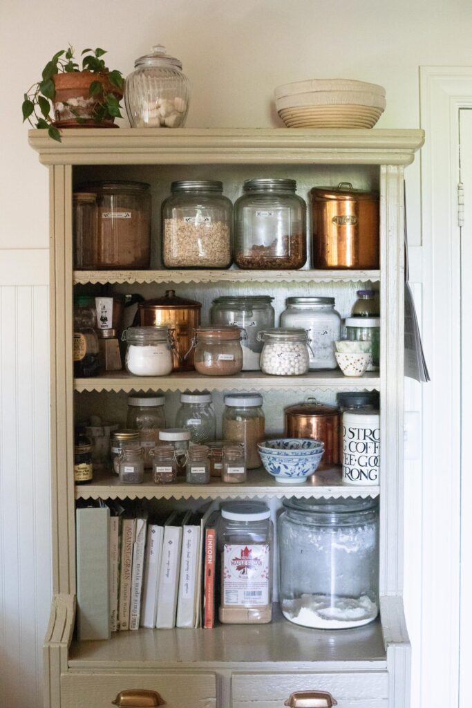 Image of a secondhand cabinet filled with thrifted and antique kitchen items in a Swedish Cottage kitchen