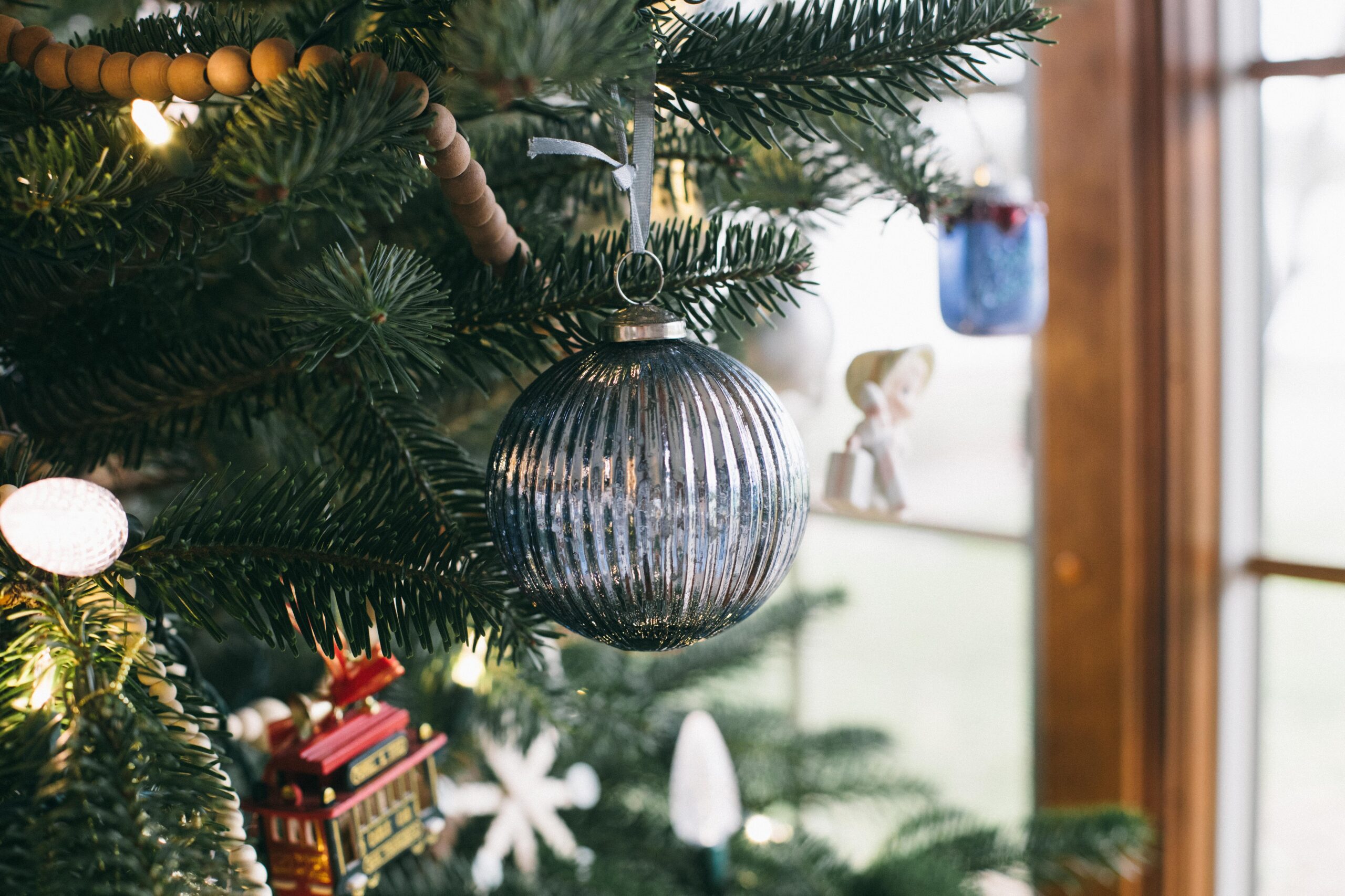Image of a cottage Christmas tree with a wood bead garland and blue ornaments