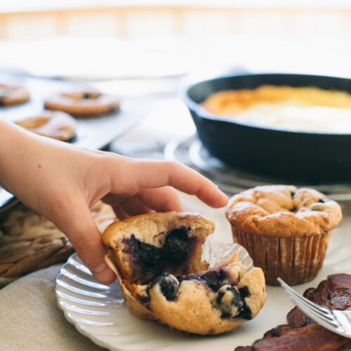 Image of a child's hand reaching for an Einkorn Blueberry Muffin