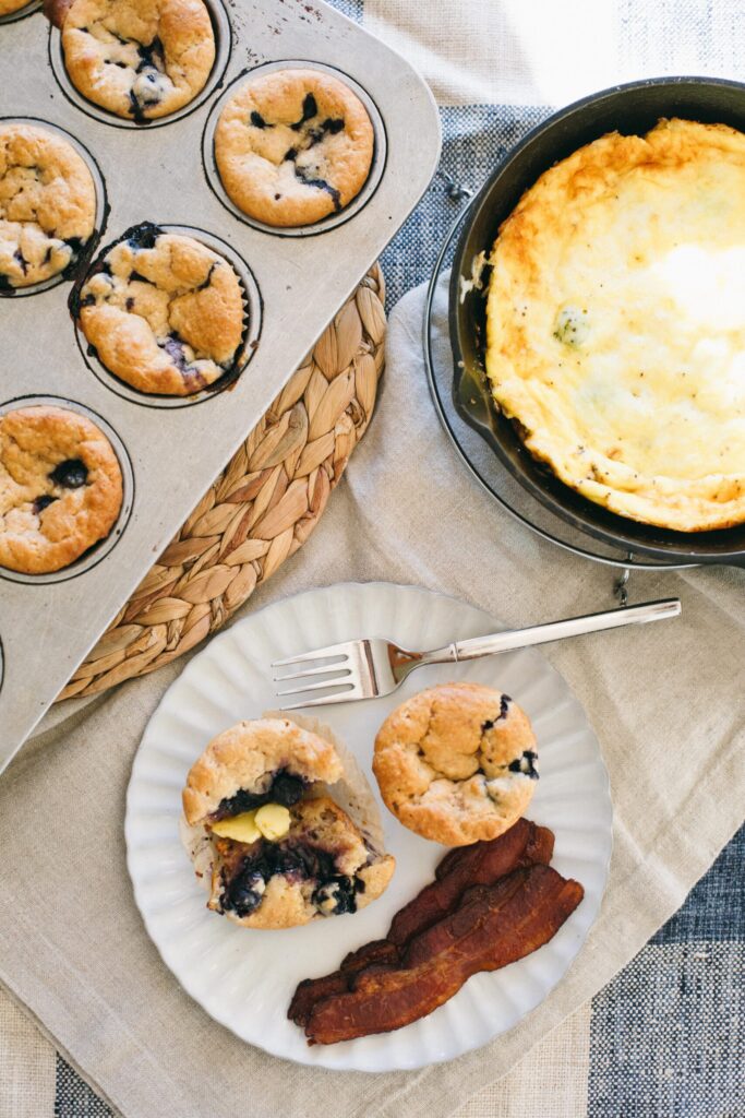 Image of a breakfast table with Einkorn Blueberry Muffins, frittata and bacon