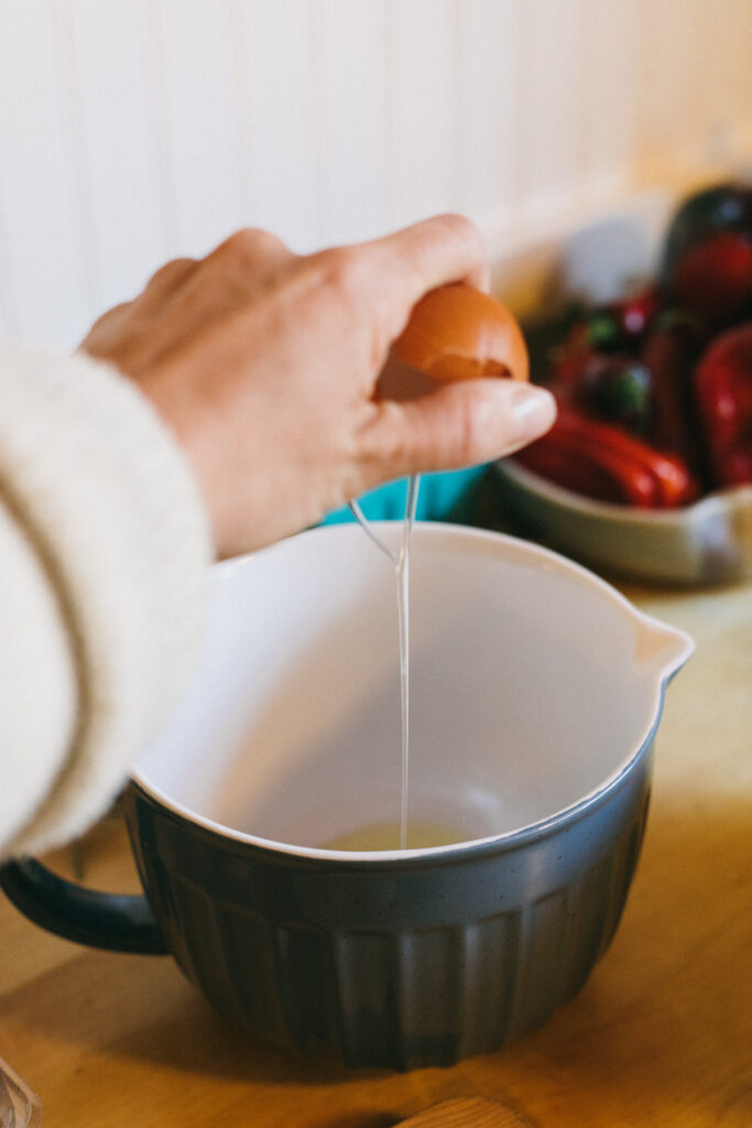 Image of a woman cracking an egg into a mixing bowl